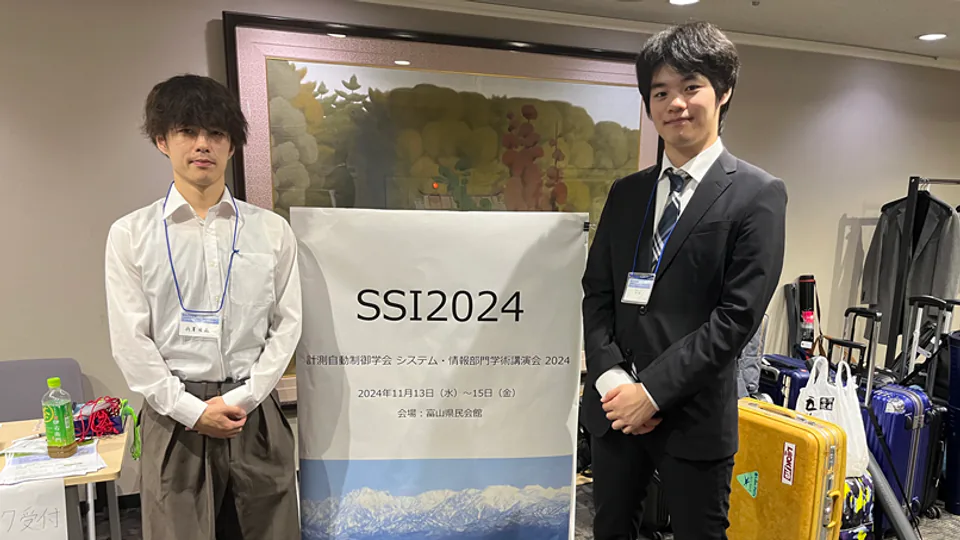 SSI 2024会場の案内看板前で参加者と並ぶ岩本侑哉